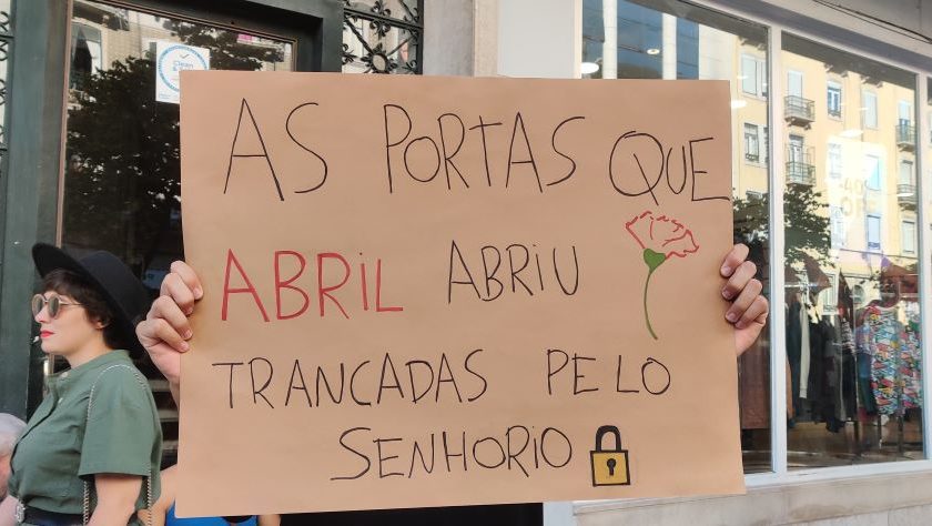 magem da manifestação pelo direito à casa em Lisboa, em 30 de Setembro de 2023. A imagem mostra um cartaz que diz "As portas que Abril abril trancadas pelo senhorio", uma referência à revolução anti-fascista de 25 de Abril de 1974.