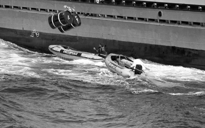 ativista ambiental arrisca a vida no mar interceptando barris a cair na água com lancha motora - 1980