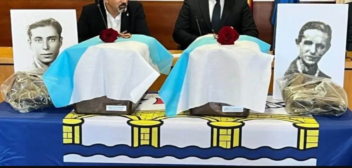Foto da entrega dos restos dos guerrilheiros, com duas fotografias deles e dois caixões cobertos da bandeira galega e uma rosa vermelha