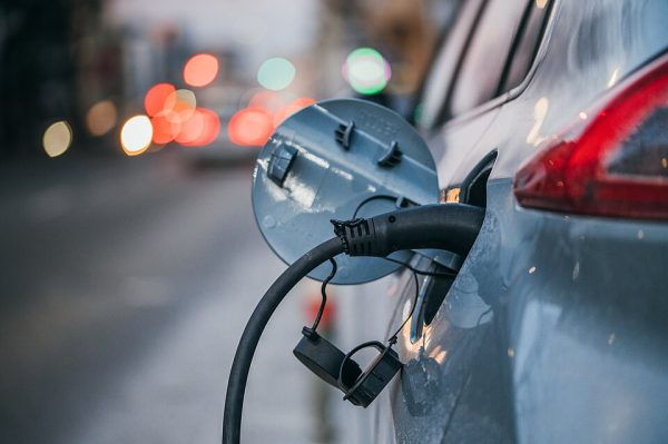 Detalhe de carro elétrico a ser carregado através do depósito de combustível