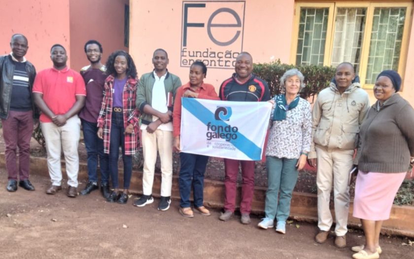 pessoas da fundação e do fundo galego à porta da escola segurando uma bandeira galega