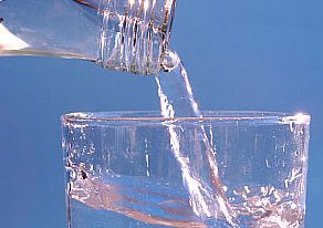 Água a ser servida num copo de uma garrafa