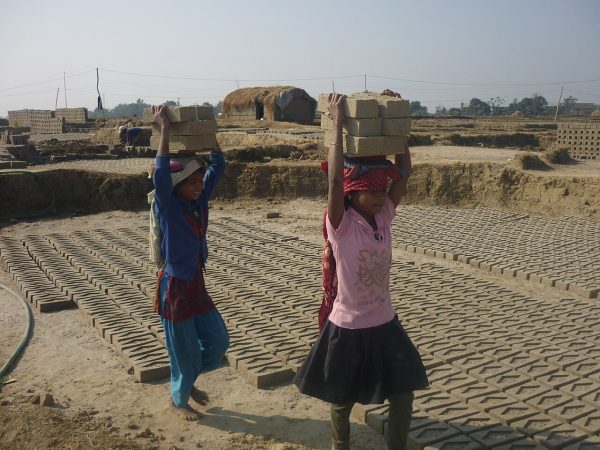 duas crianças carregando tijolos à cabeça no Nepal
