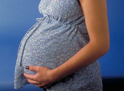imagem de barriga duma grávida com vestido de flores azul