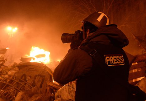 jornalista a tirar fotografia num cenário de violência com lume