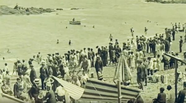fotograma do filme em que se veem pessoas na praia de Riaçor na Corunha, vestidos com fatos da época