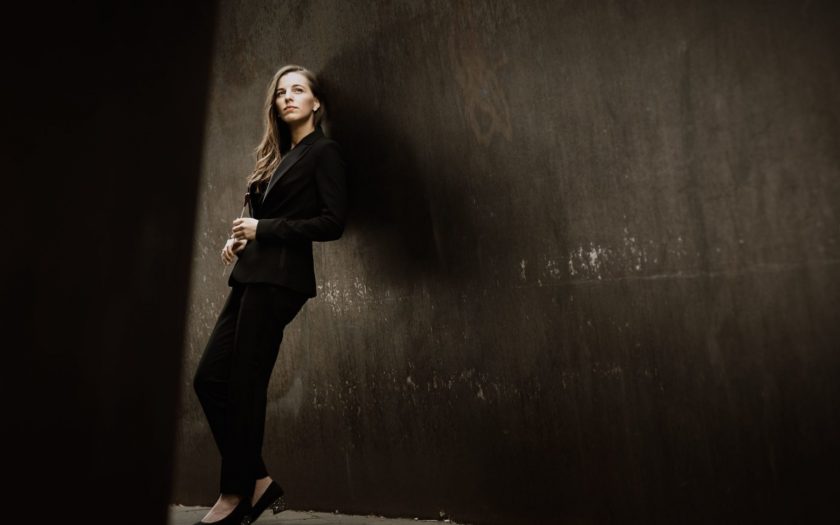 mulher apoiada contra a parede num cenário escuro