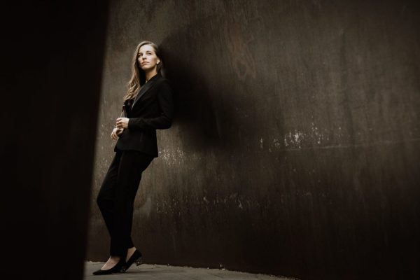 mulher apoiada contra a parede num cenário escuro