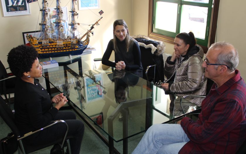 Diretora caboverdiana em reunião na Câmara ao redor duma mesa de reuniões de vidro