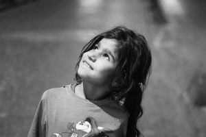 criança a olhar para o céu com esperança