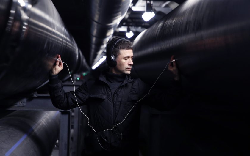 imagem promocional do evento com o autor a ouvir materiais metálicos com sensores