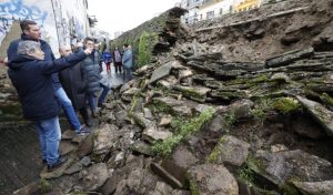 troço esvoroado da muralha com pessoas defronte olhando para os estragos