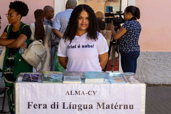 Jovem mulher com t-shirt branca com texto "Kriol é sabe"