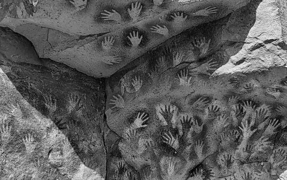 pintura rupestre a Preto e Branco com mãos humanas de muitos tamanhos e cores